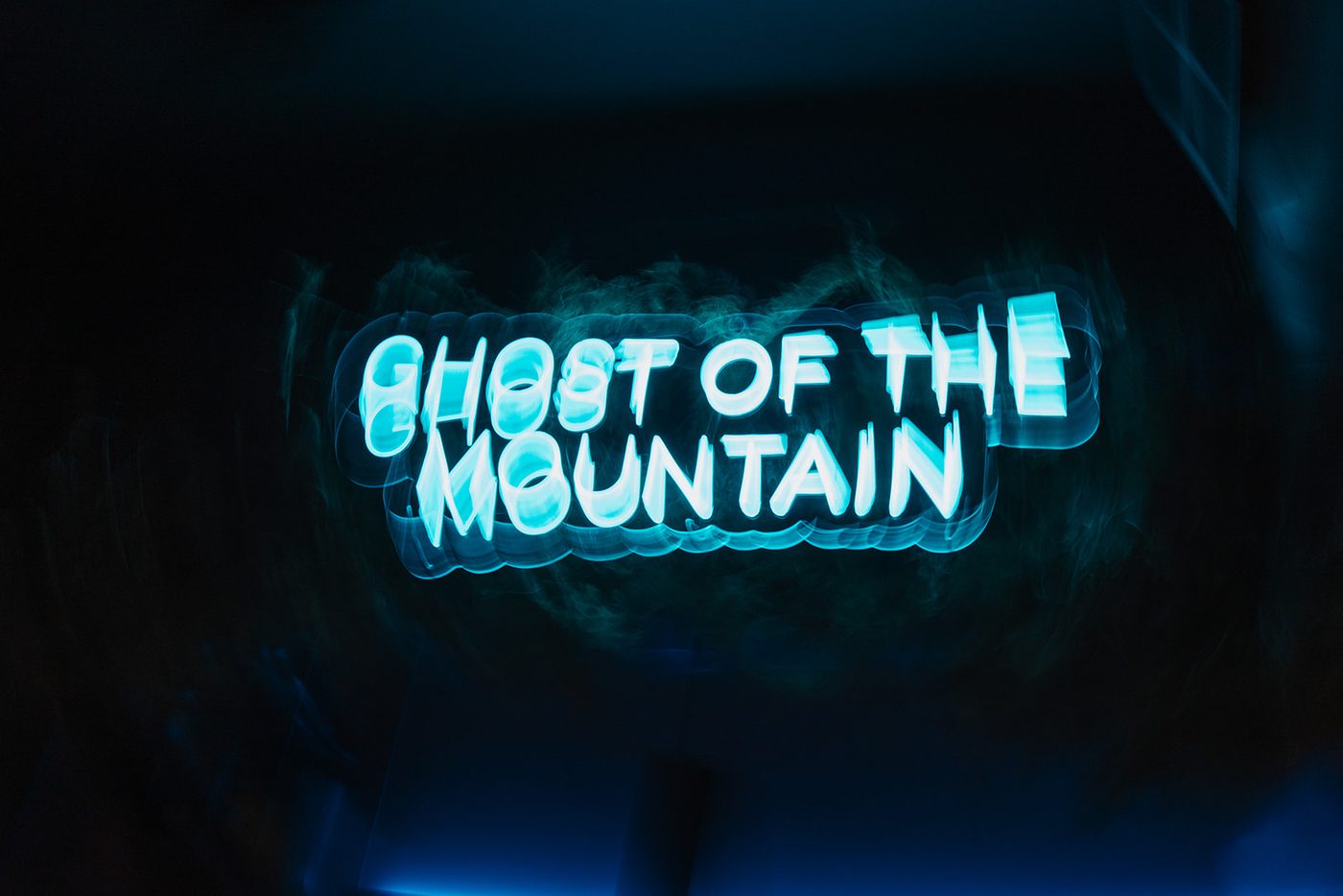 A guest under the Ghost of the Mountain neon sign at Snow Leopard Barbershop